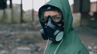 环境污染和生物危害。一个戴防毒面具的人在废弃建筑附近视频素材模板下载