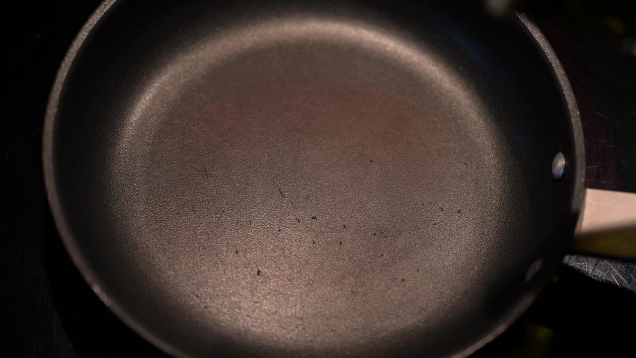 将橄榄油缓缓倒入煎锅中，然后摊开。