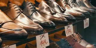 鞋店橱窗里的货架上摆放着各种颜色的经典皮革男鞋，上面贴着打折的价签