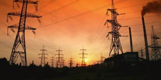 红色夜空下的输电线路。在美丽的日落下，电线与大自然中的高压电力塔。夕阳下的电线。