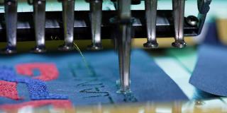 制衣机正在缝线。自动绣花机在蓝布上的工作。缝纫针在织物上快速移动。特写镜头。