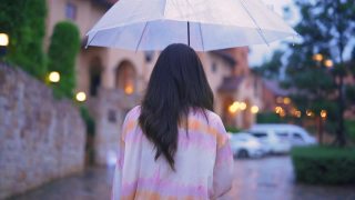 亚洲年轻女子走在下雨的街道伞下。视频素材模板下载