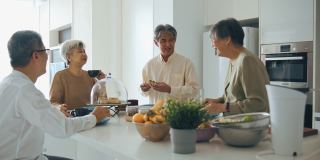 4位亚洲华人老年朋友在周末下午的厨房柜台社交聚会中享受茶歇