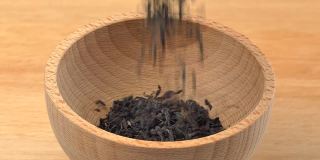 云南红茶倒入木质背景上的木碗中。缓慢的运动。