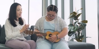 唐氏综合症女孩和她的妈妈在她的度假屋弹吉他。