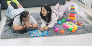 患有唐氏综合症的女孩正在家里和妈妈一起练习玩玩具。