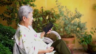 亚洲老人，亚洲老人，年长的老妇人在户外用智能手机聊天视频素材模板下载