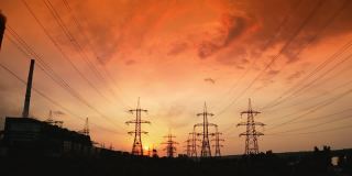 红色的日出和电线。水电输电线塔构成电网。日落时的电力塔全景。运动镜头。