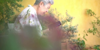 亚洲老人，亚洲老人，年长的老妇人在户外用智能手机聊天