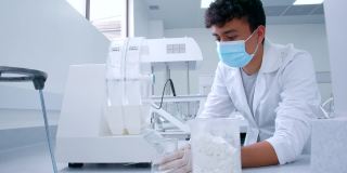 拉丁美洲的一名男学生戴着防护手套和口罩在科学实验室的机器上添加样本