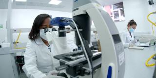 非裔美国女科学家在实验室工作，通过显微镜观察样本