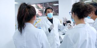 一位拉丁美洲教师在实验室里一边讲解一边向一群理科学生展示一个样本