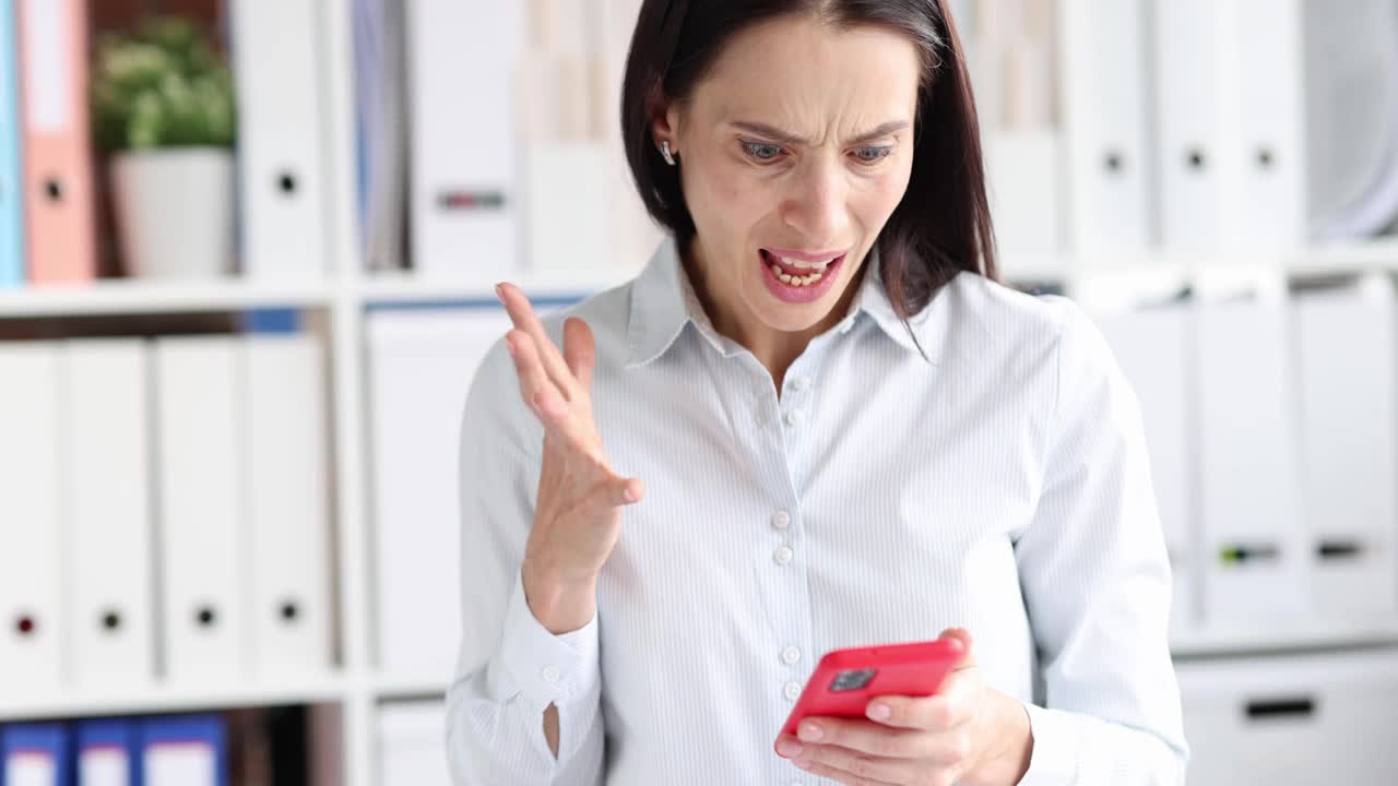 愤怒的女人在办公室里看着手机屏幕大喊大叫4k电影的慢动作