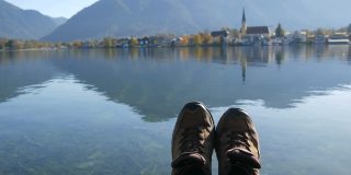 秋天的德国巴伐利亚，在泰根西湖乘船旅行。游客们站在前台。徒步旅行的女人靴子近距离。旅游理念繁荣幸福快乐