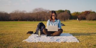 年轻女子戴着智能眼镜，在公园里使用笔记本电脑。年轻女子活跃在增强现实元宇宙中。