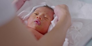 妈妈在宝宝洗完澡后给他盖上毛巾让他干得舒服些。新生婴儿看着她的妈妈用爱擦干她的身体。婴儿新生儿护理和母亲节概念