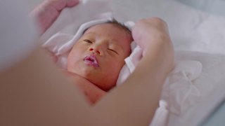 妈妈在宝宝洗完澡后给他盖上毛巾让他干得舒服些。新生婴儿看着她的妈妈用爱擦干她的身体。婴儿新生儿护理和母亲节概念视频素材模板下载