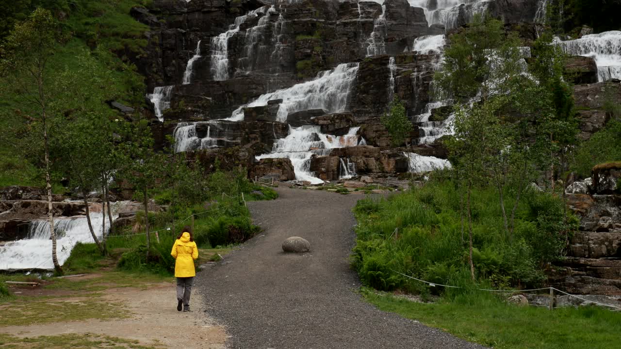 沃斯、Hordaland、挪威。瀑布电视在春天。年轻的白人妇女女士游客旅行者步行参观挪威最高的瀑布。著名的挪威地标和热门目的地