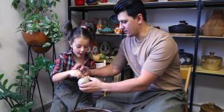 爸爸和女儿正在准备一个陶轮，以便在上面安装一块粘土坯