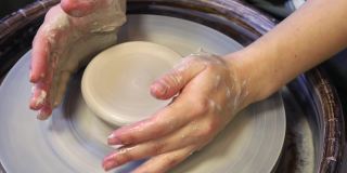 陶工大师的手向学生的手展示了陶工施加的正确压力
