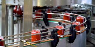 蔬菜加工自动化生产线。玻璃罐和蔬菜意大利面在传送带上。把番茄酱装在玻璃瓶里。