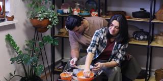 一对年轻的夫妇画了一个简单的图案，用海绵浸泡在陶工轮上制作的陶土杯上