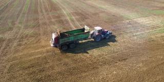 一辆拖拉机在农场附近的田地上施有机肥。给土壤施肥以获得更好的收成。前视图。