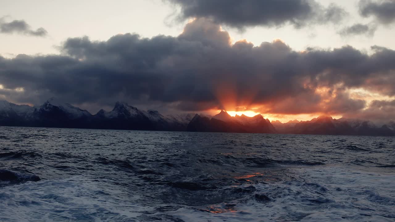 夕阳在波涛汹涌的海面上，带着一艘小船从开阔的大海上驶来
