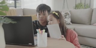 亚洲混血儿童在家用笔记本电脑视频通话，使用在线虚拟课堂，社交距离，在家上学，电子学习，新常态概念