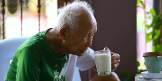 一个九十多岁的亚洲人坐在家里，在他的辛苦工作中放松他的一生。
