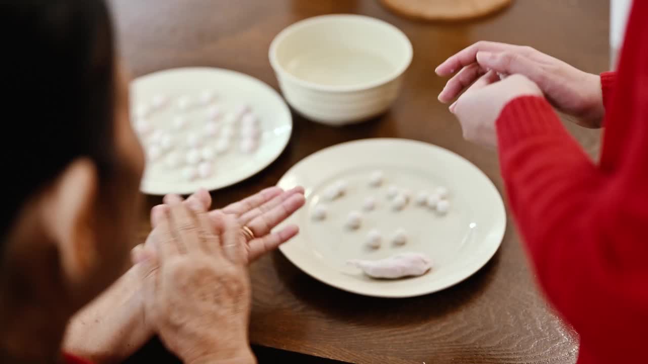 一位亚洲的祖母和她的孙女准备制作汤圆庆祝中国新年