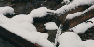 大雪干净、透明的山涧溪水顺着木沟流入特制的水槽