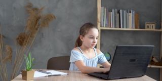 十几岁的女学生在家里用笔记本电脑做作业。这个孩子使用电子设备学习。儿童教育和远程学习。