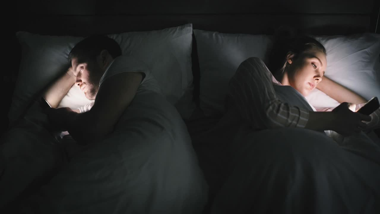一对夫妇在家里的床上用手机无视对方的4k视频