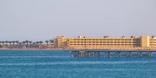 热带度假胜地的海岸线，棕榈树，酒店建筑和蓝色的海水在前面