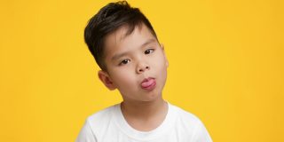 一个日本小男孩在黄色背景下伸出舌头