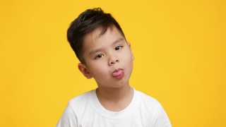 一个日本小男孩在黄色背景下伸出舌头视频素材模板下载