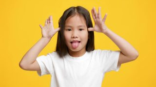搞笑的韩国小女孩伸出舌头做鬼脸，黄色背景视频素材模板下载