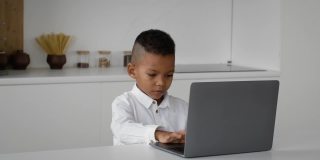 在线教育可爱的小黑人男孩在家里用笔记本电脑打字