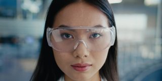 韩国女科学家在室内戴防护眼镜，穿着实验室工作服