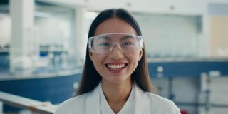 戴着防护眼镜的韩国女制造技师站在室内大笑