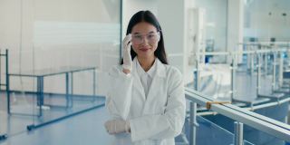 亚洲女士在室内脱掉防护眼镜，穿着实验室外套