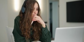 专心致志的女学生戴着耳机在笔记本电脑上做笔记，进行远程教学