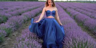 7月，法国普罗旺斯，一位身着连衣裙的美丽年轻女子漫步在盛开的薰衣草地里。暑假旅游背景。