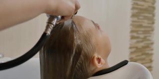 理发师的手把水倒在一个十几岁女孩的头发上
