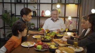 快乐的亚洲家庭围坐在餐桌前享受晚餐。视频素材模板下载