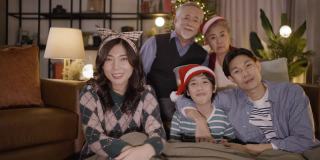 亚洲家庭在圣诞节晚上坐在一起看电视。家庭，世代，圣诞节和人的概念