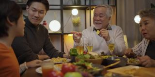 快乐的亚洲家庭围坐在餐桌前享受晚餐。
