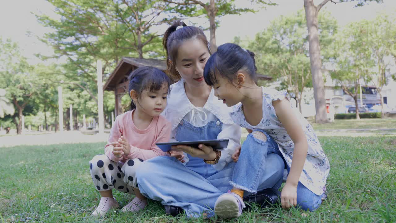 母亲和孩子在公园里使用数码平板电脑