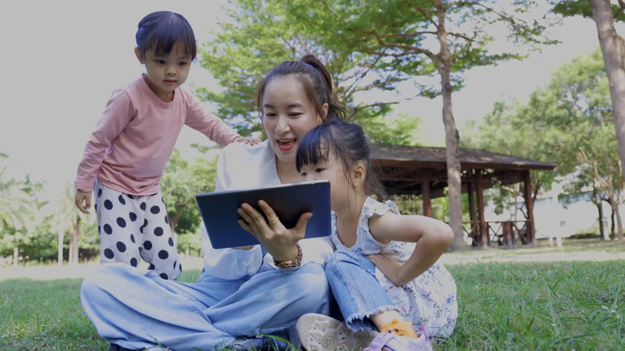 妈妈和孩子们在公园里用数码平板电脑进行视频通话